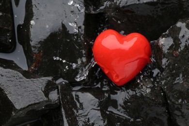 Photo of Red decorative heart on stones and water, top view. Space for text