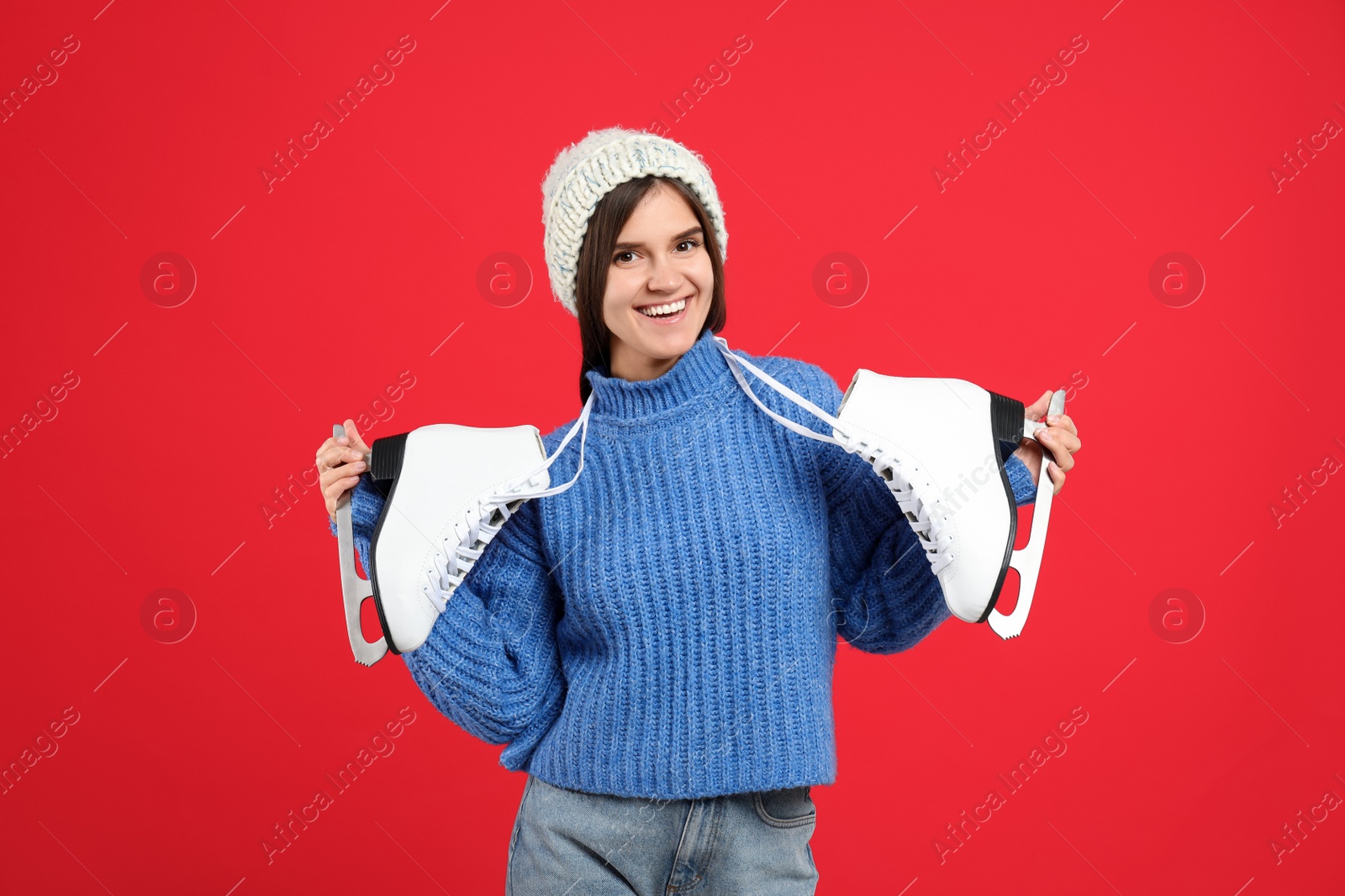 Photo of Happy woman with ice skates on red background