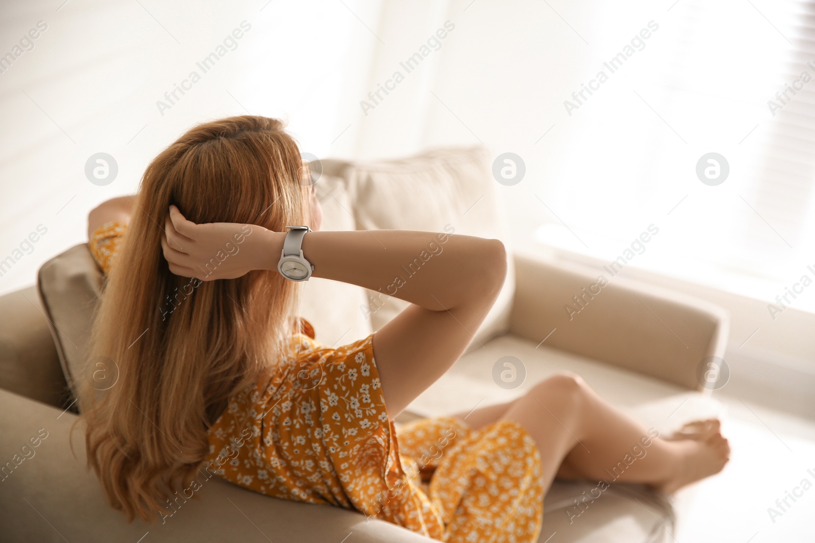 Photo of Young woman relaxing on couch near window at home