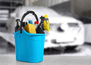 Image of Bucket with cleaning supplies on grey table at car wash. Space for text