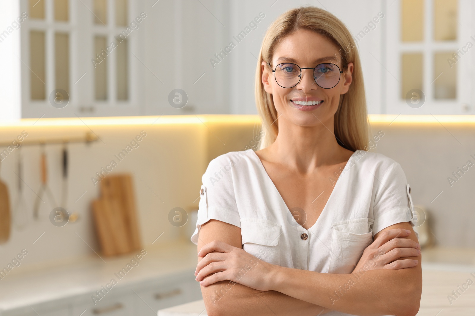 Photo of Portrait of smiling woman with stylish glasses in kitchen. Space for text