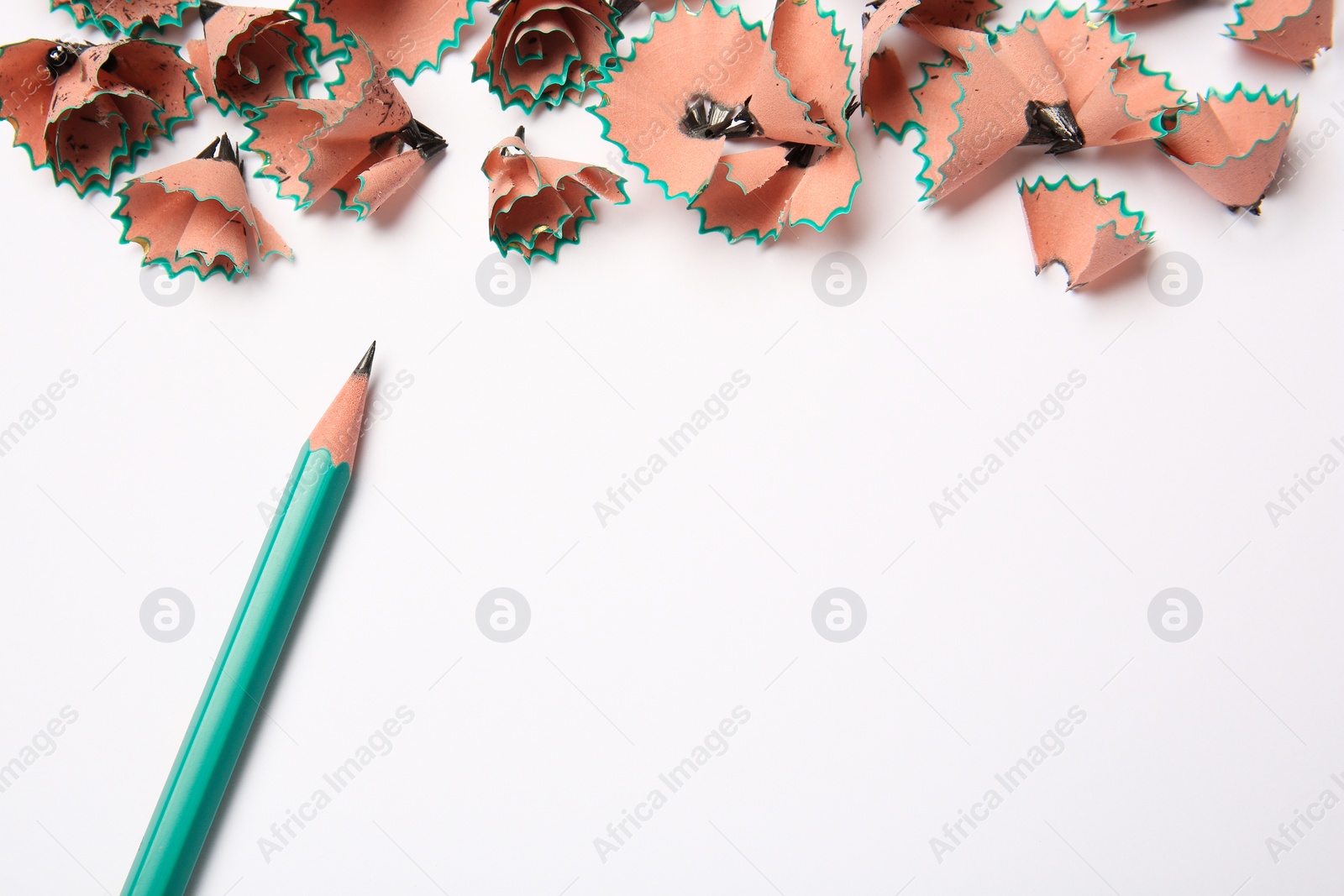 Photo of Sharp graphite pencil and shavings on white background, top view. Space for text