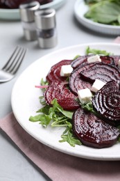 Photo of Roasted beetroot slices with feta cheese and arugula on light grey table, closeup