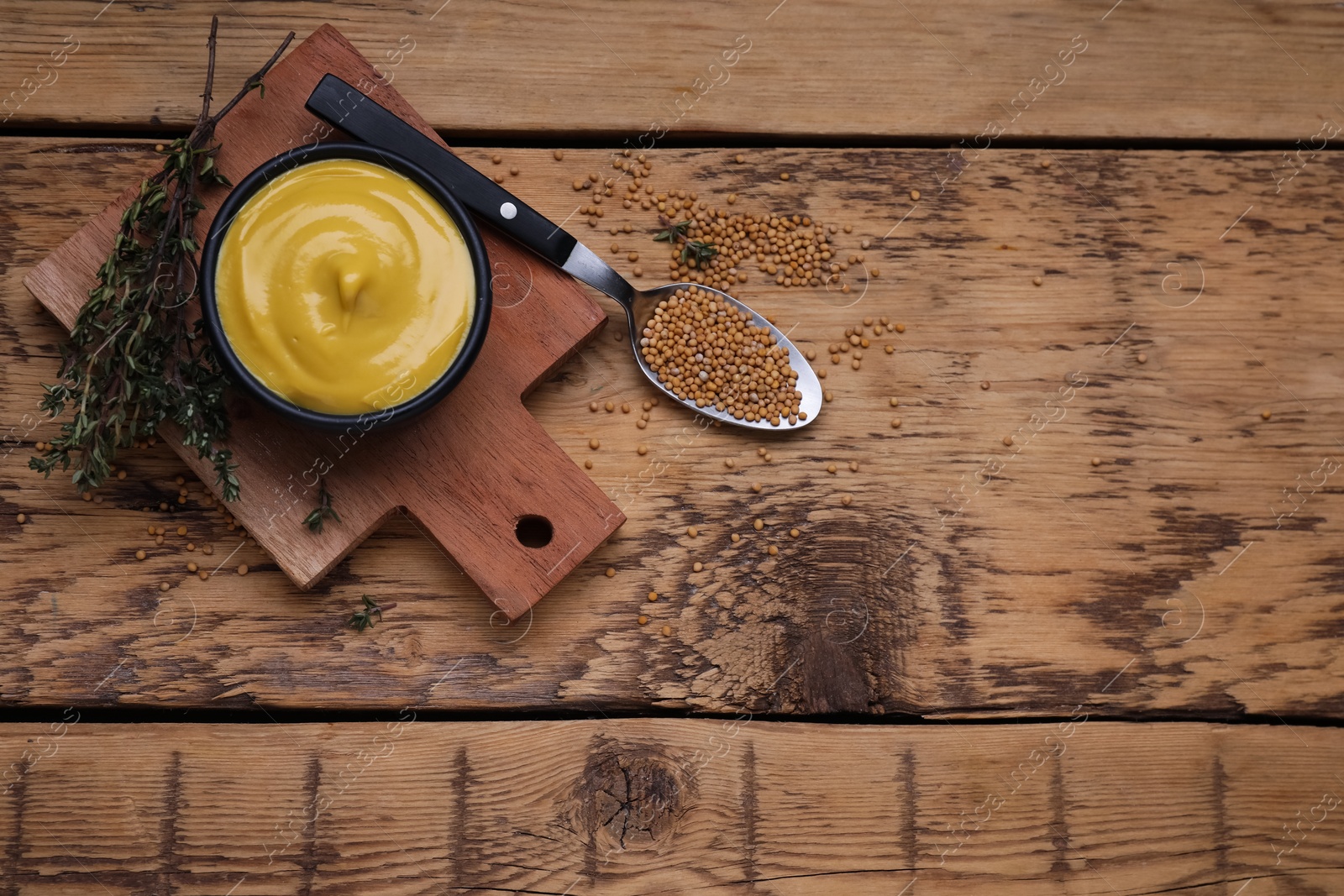 Photo of Delicious mustard, seeds and thyme on wooden table, flat lay. Space for text