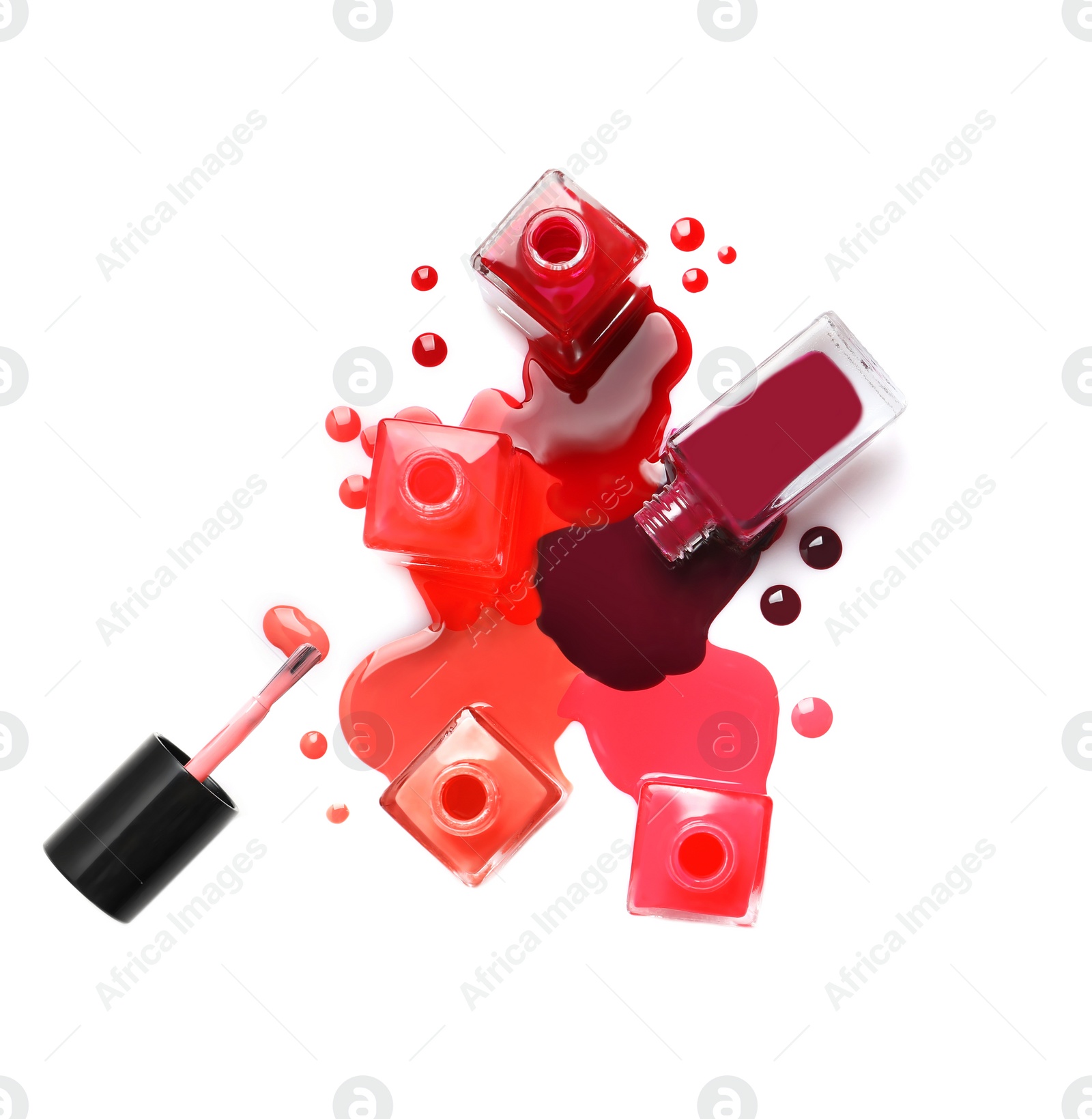 Photo of Spilled different nail polishes with bottles on white background, top view