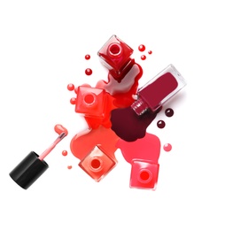 Spilled different nail polishes with bottles on white background, top view