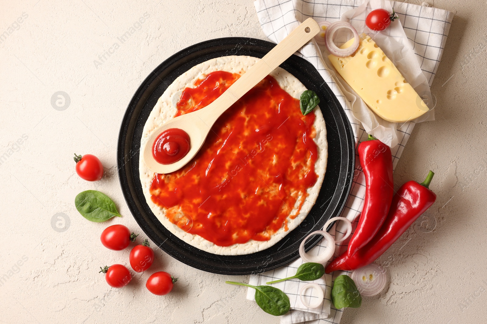 Photo of Pizza base smeared with tomato sauce and products on light textured table, flat lay