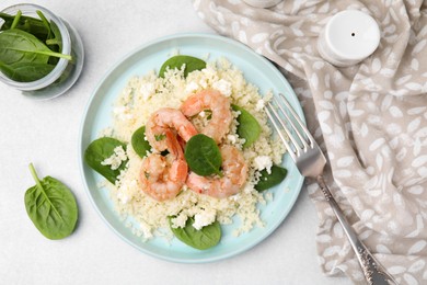 Photo of Delicious couscous with shrimps and spinach served on white table, flat lay