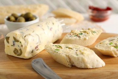 Photo of Tasty butter with olives, green onion and bread on wooden board, closeup