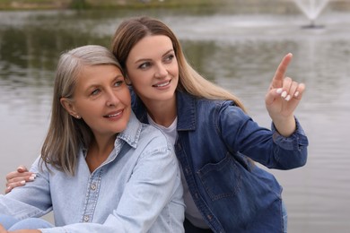 Photo of Happy mature mother and her daughter near pond