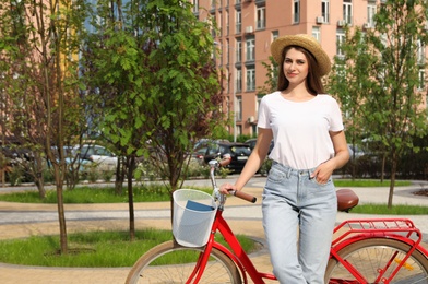 Photo of Young woman near modern color bicycle outside. Space for text