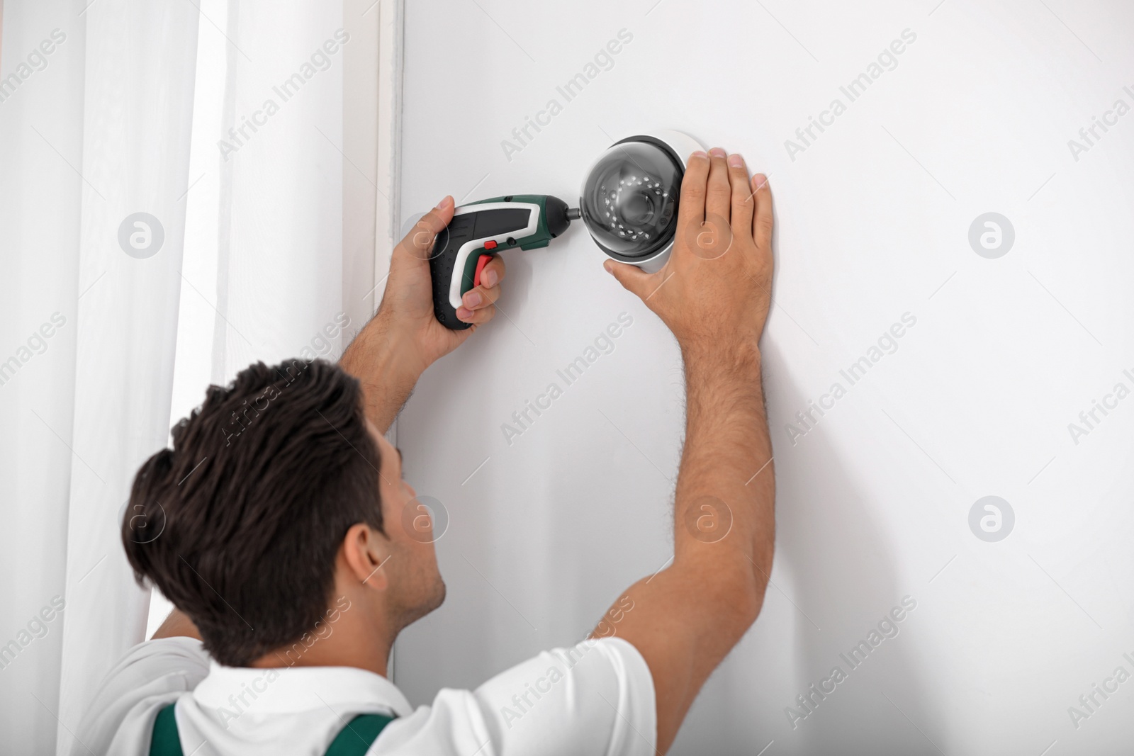 Photo of Technician installing CCTV camera on wall indoors