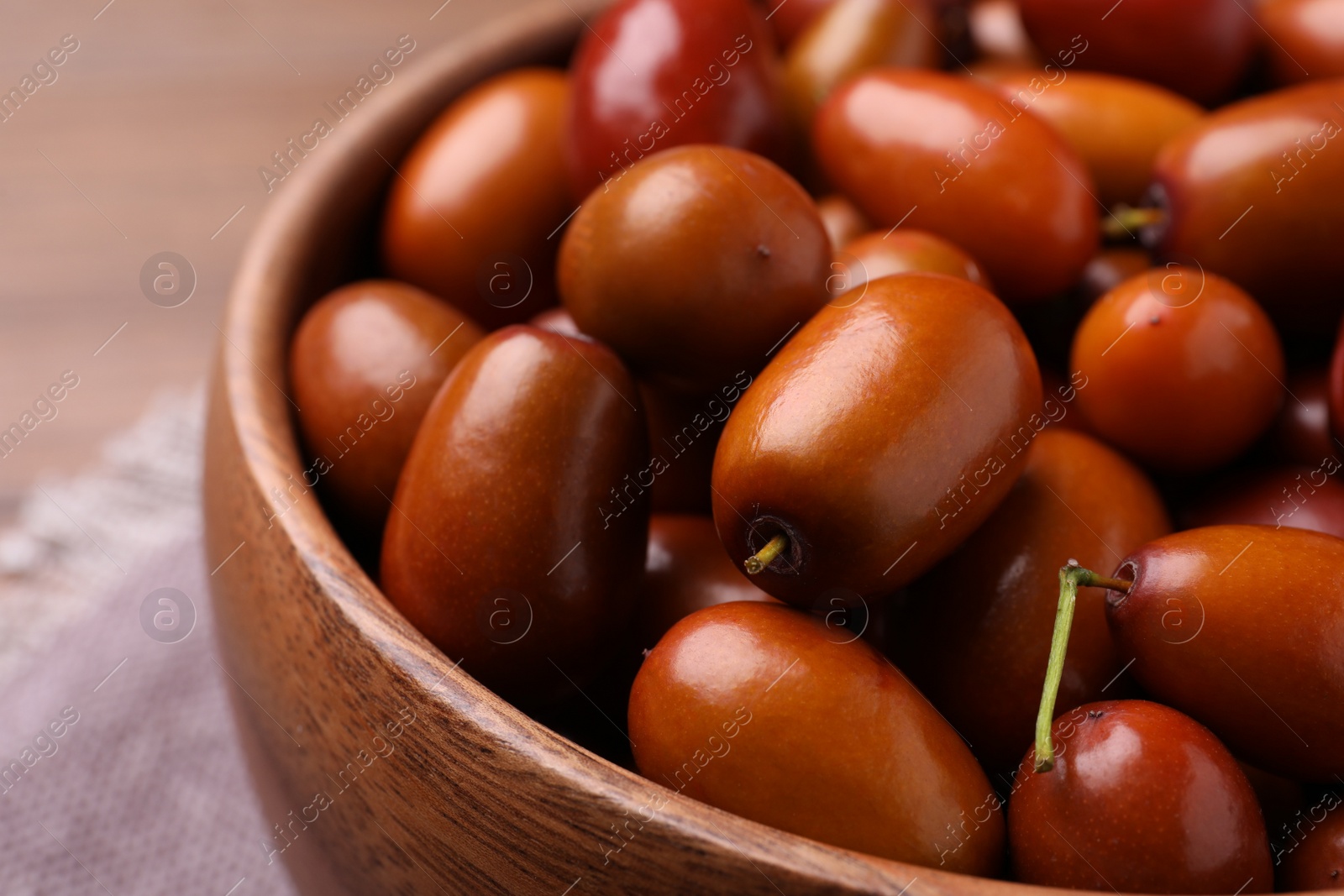 Photo of Fresh Ziziphus jujuba fruits in wooden bowl, closeup