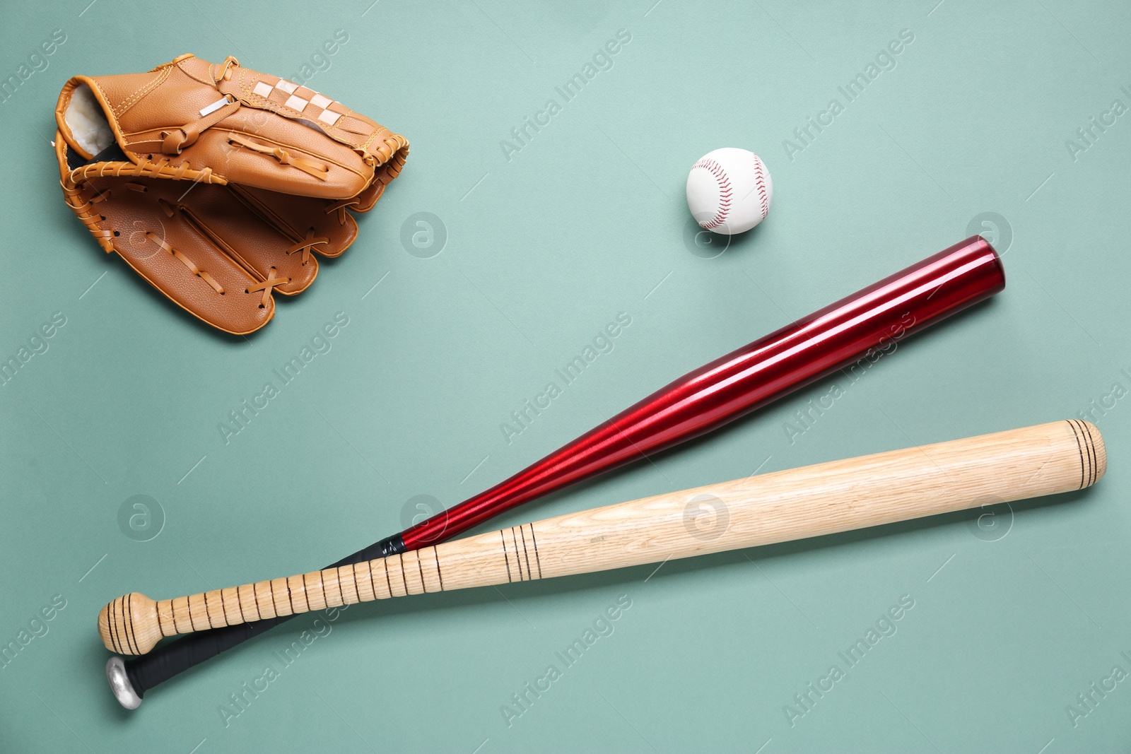 Photo of Baseball glove, bats and ball on pale green background, flat lay