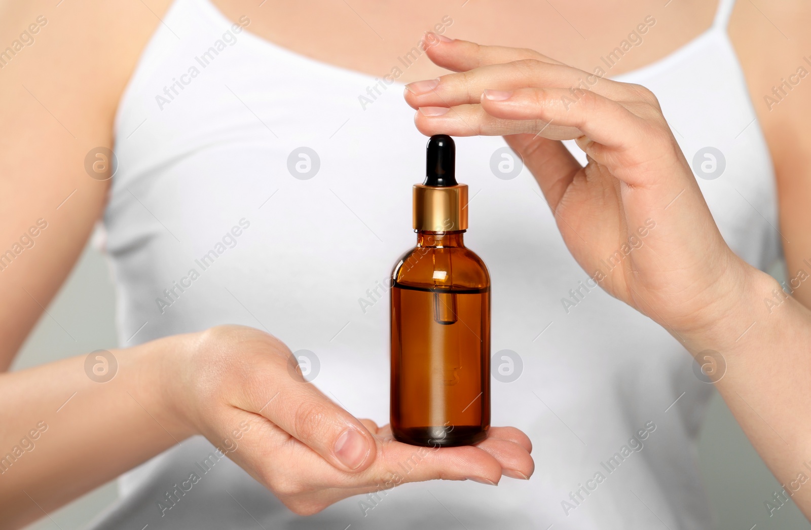 Photo of Woman holding bottle of essential oil on white background, closeup