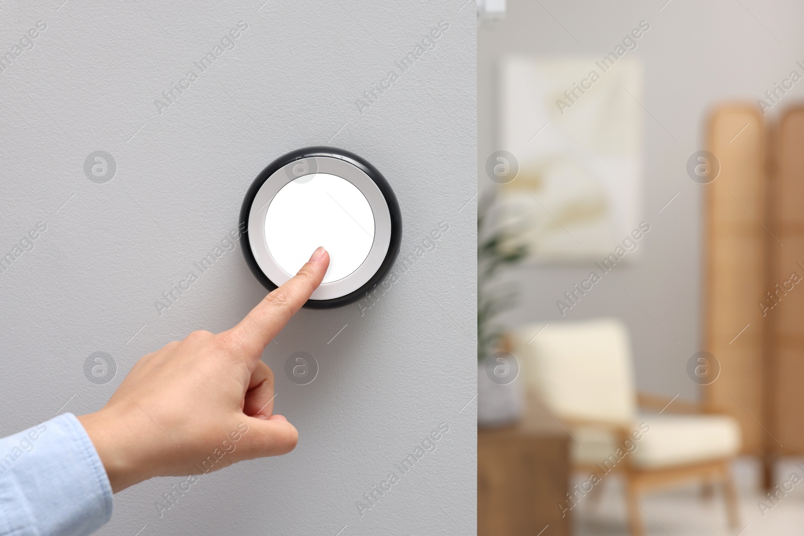 Photo of Woman adjusting thermostat on white wall indoors, closeup and space for text. Smart home system