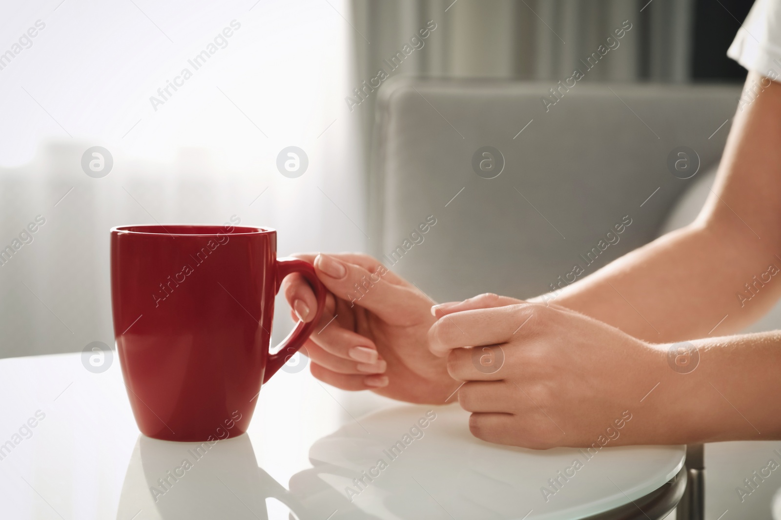Photo of Woman with red cup at table indoors, closeup