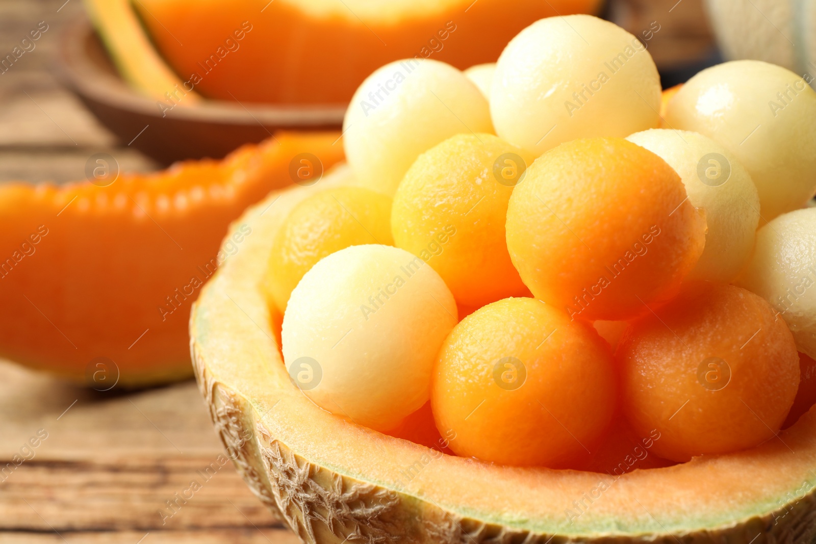 Photo of Different melon balls on wooden table, closeup