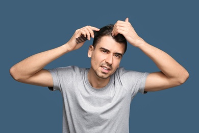 Photo of Young man with hair loss problem on color background