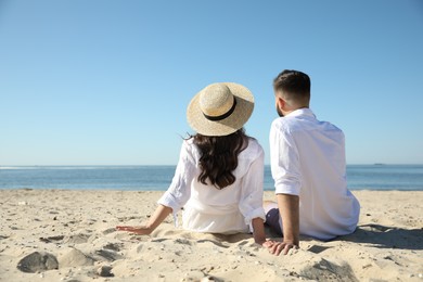 Young couple on beach near sea, back view. Honeymoon trip