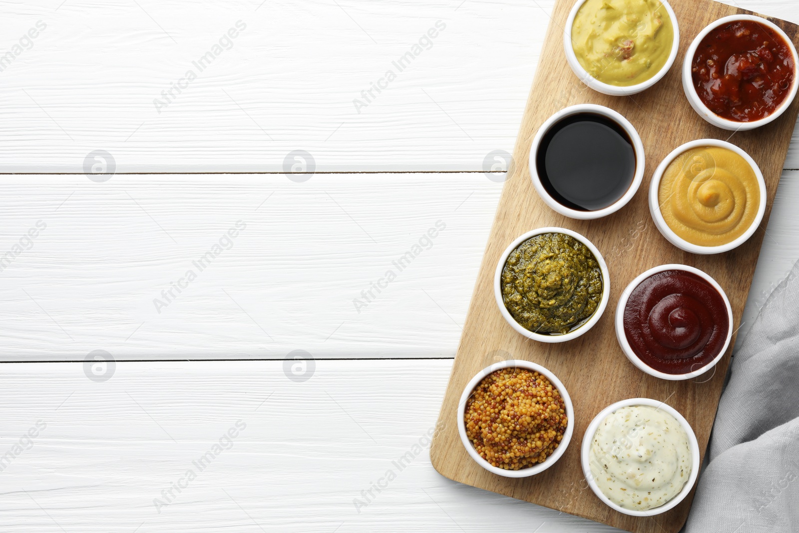 Photo of Many different sauces in bowls on white wooden table, top view. Space for text