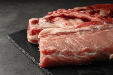 Slate plate with raw meat on grey table, closeup