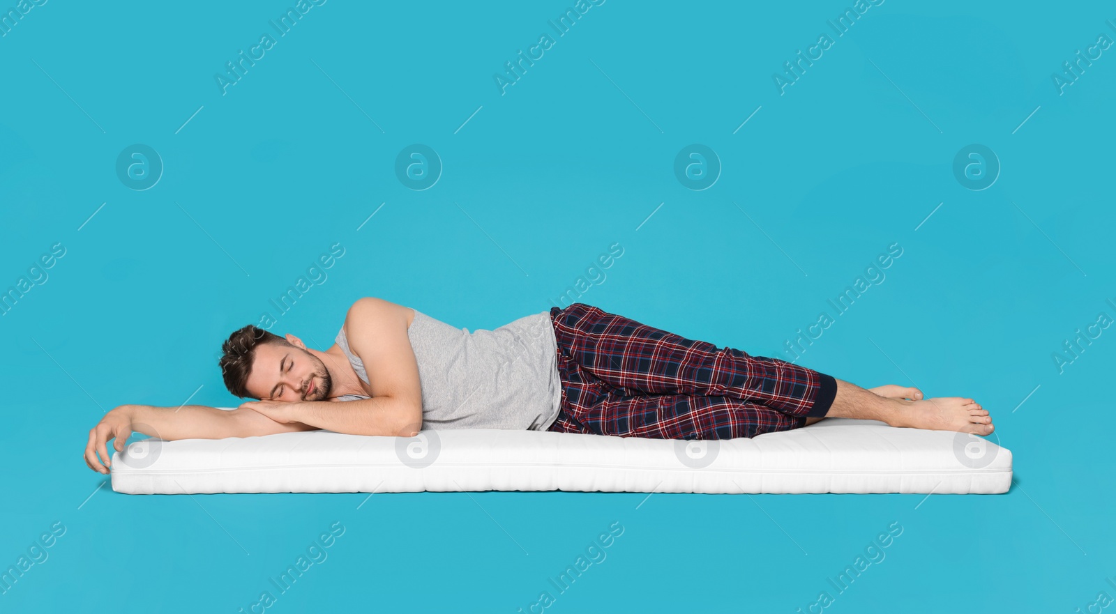 Photo of Man sleeping on soft mattress against light blue background