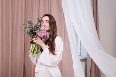 Beautiful young woman with bouquet of flowers indoors