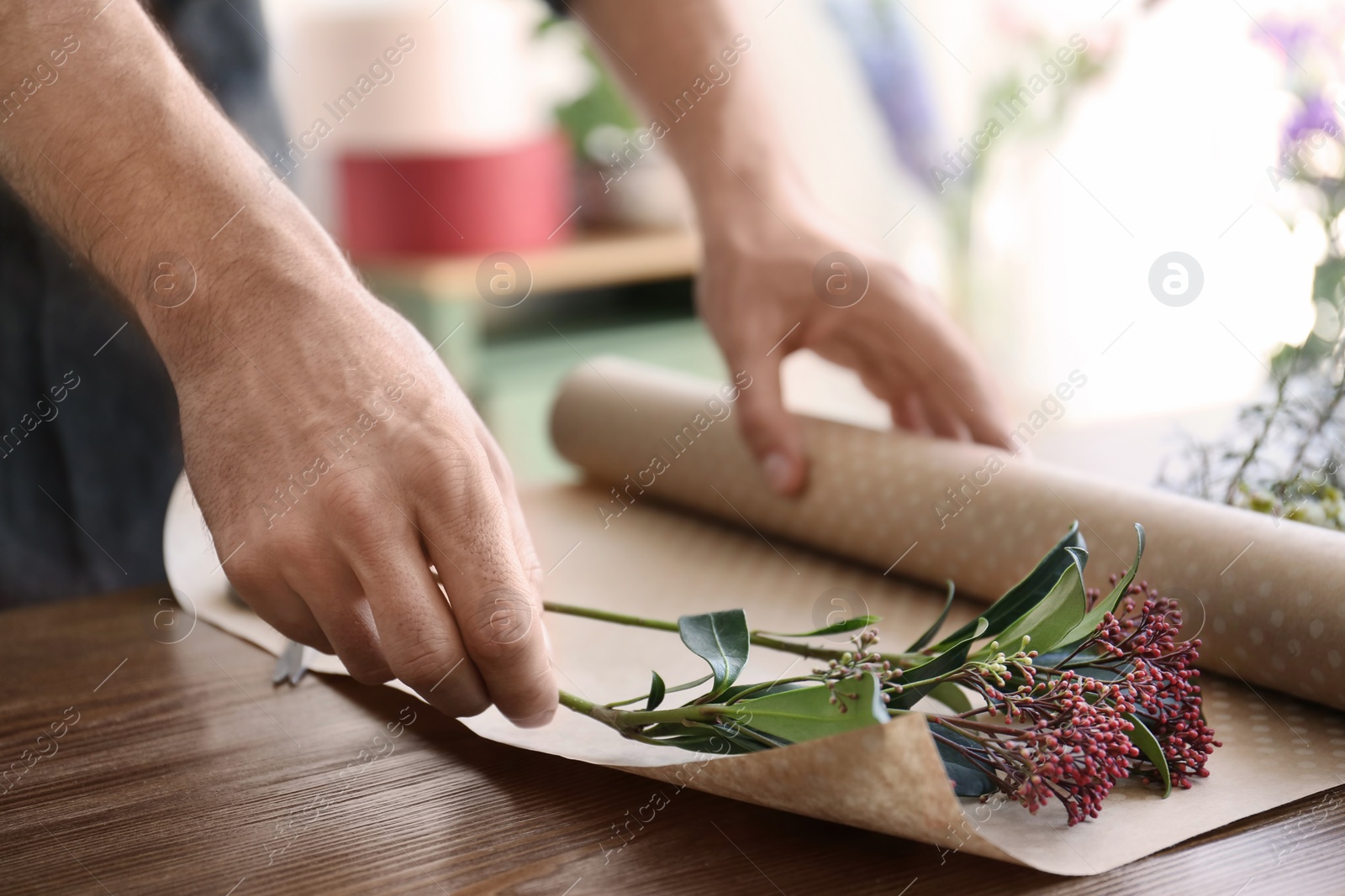 Photo of Male florist creating beautiful bouquet at table, closeup