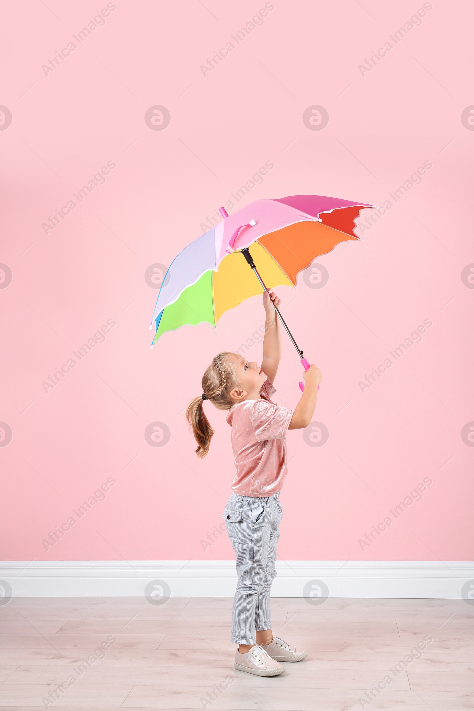 Photo of Little girl with rainbow umbrella near color wall