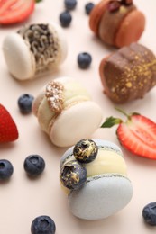 Photo of Delicious macarons and berries on beige table, closeup