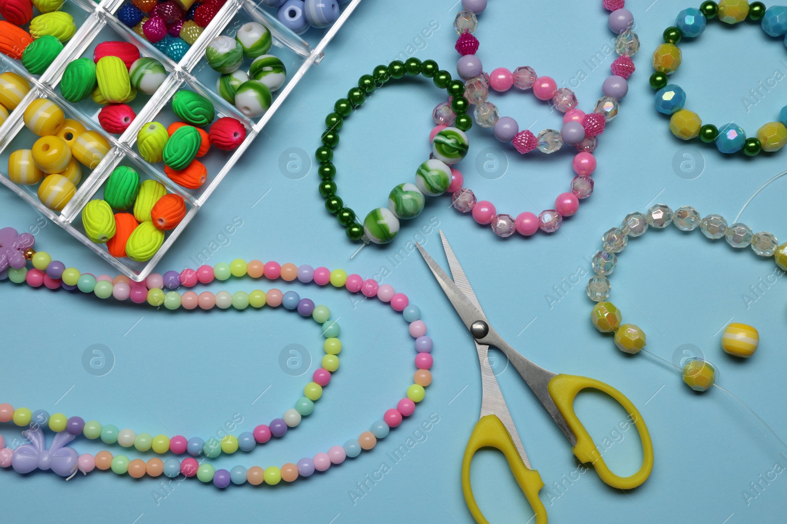 Photo of Flat lay composition with different colorful beads on light blue background