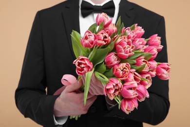 Man with beautiful bouquet on beige background, closeup