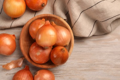 Many ripe onions on wooden table, flat lay. Space for text
