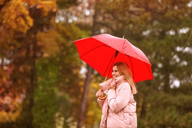 Woman with umbrella in autumn park on rainy day