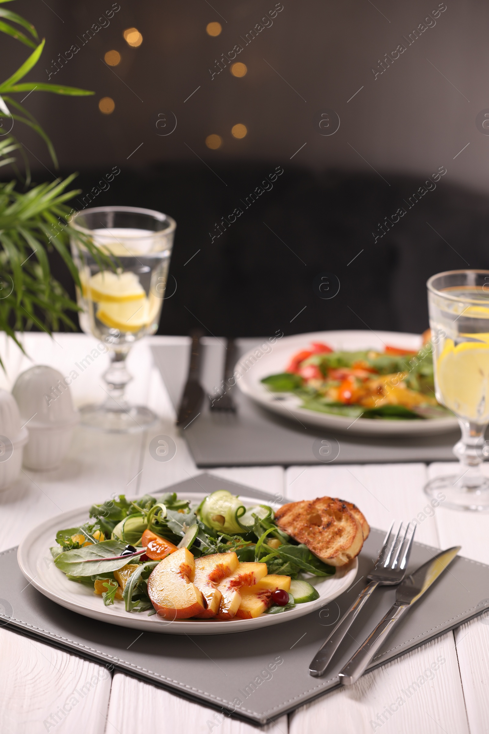 Photo of Delicious salad with peach slices served on white wooden table