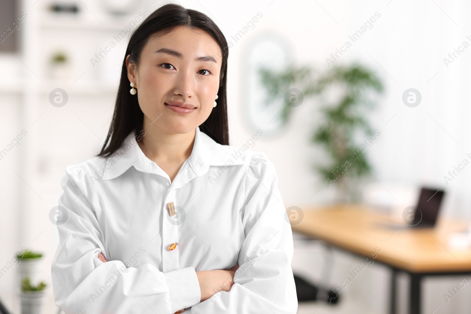Photo of Portrait of beautiful businesswoman with crossed arms in office. Space for text