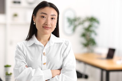 Portrait of beautiful businesswoman with crossed arms in office. Space for text