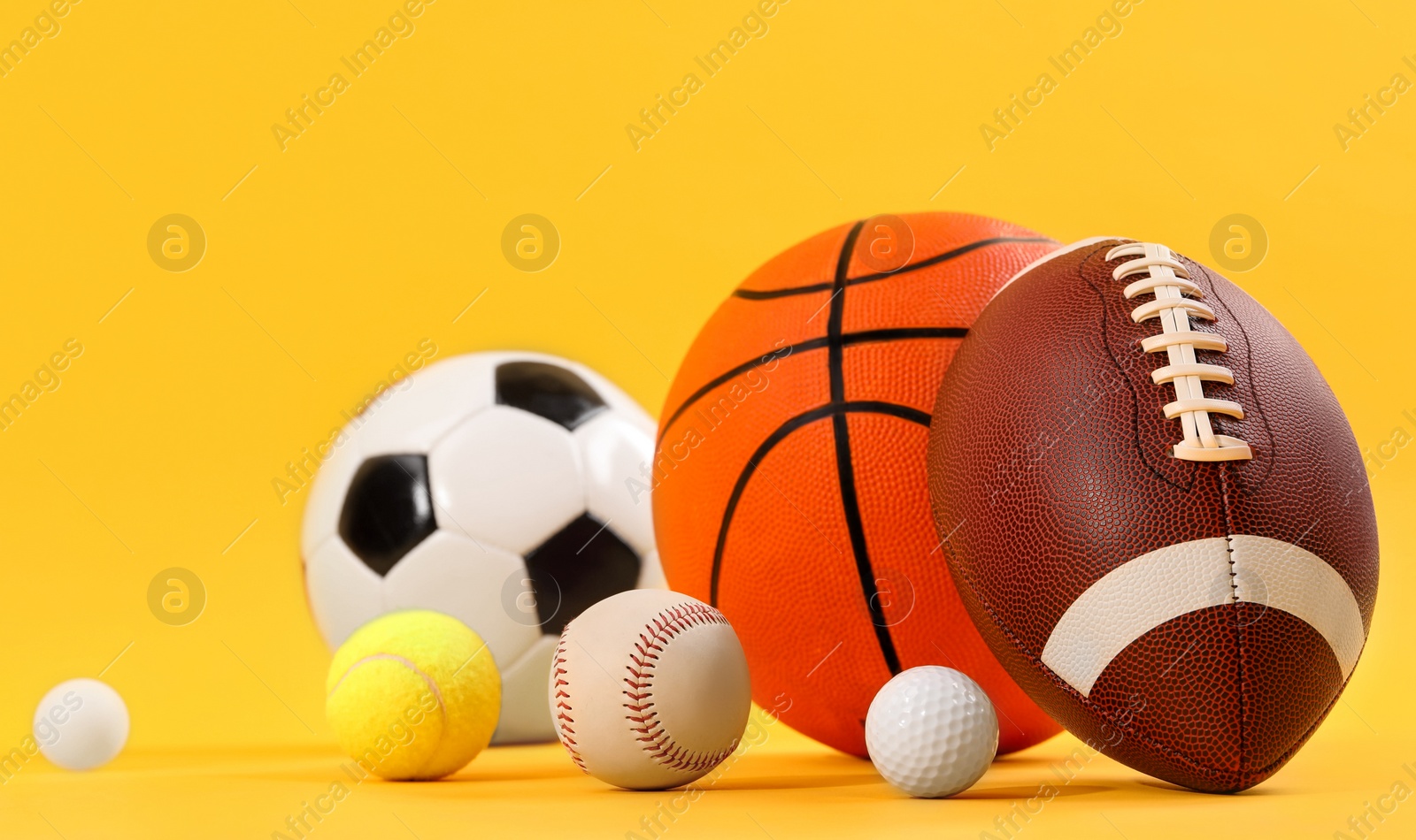 Photo of Many different sports balls on yellow background