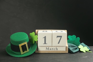 Photo of Leprechaun's hat, block calendar and St. Patrick's day decor on black background