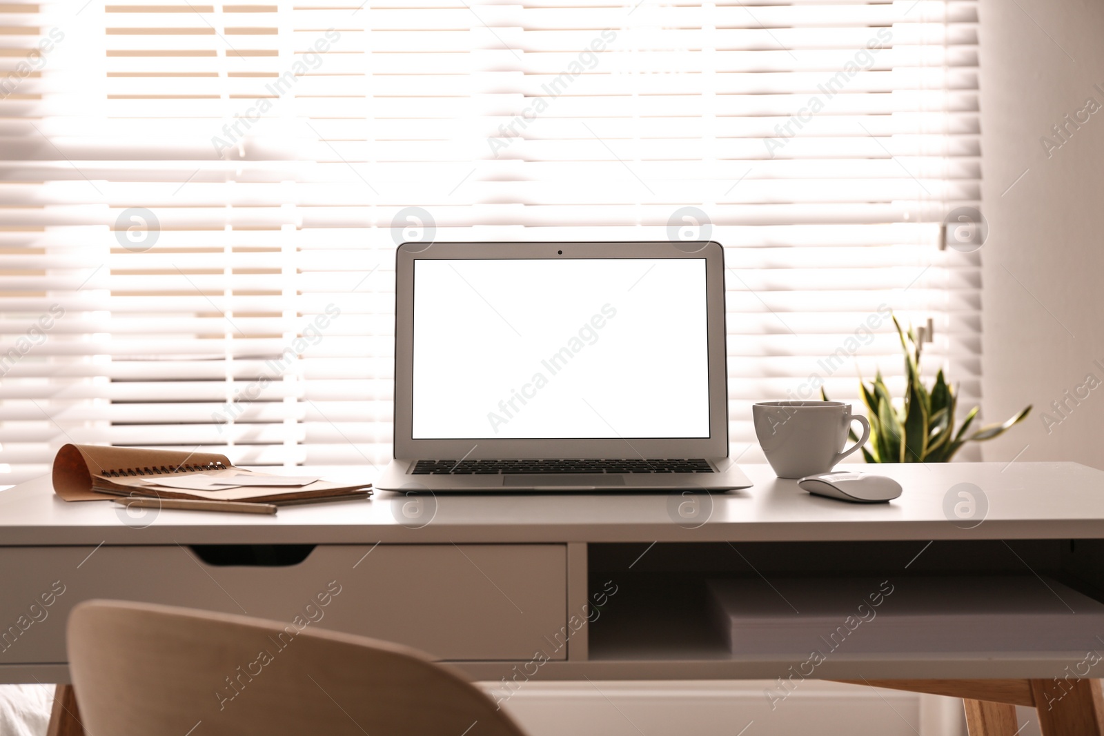 Photo of Laptop on desk near window in office. Comfortable workplace