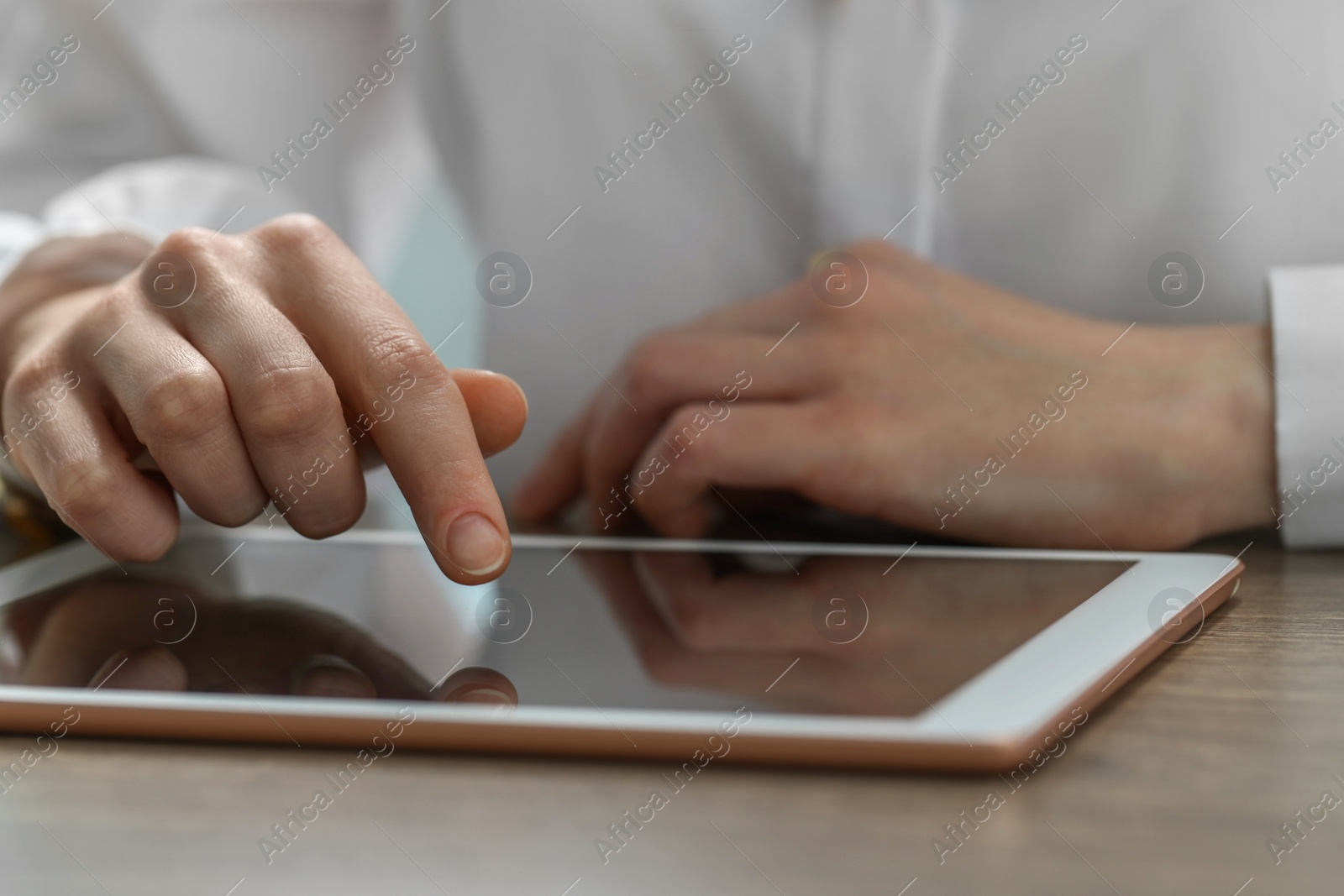 Photo of Closeup view of woman using modern tablet at table