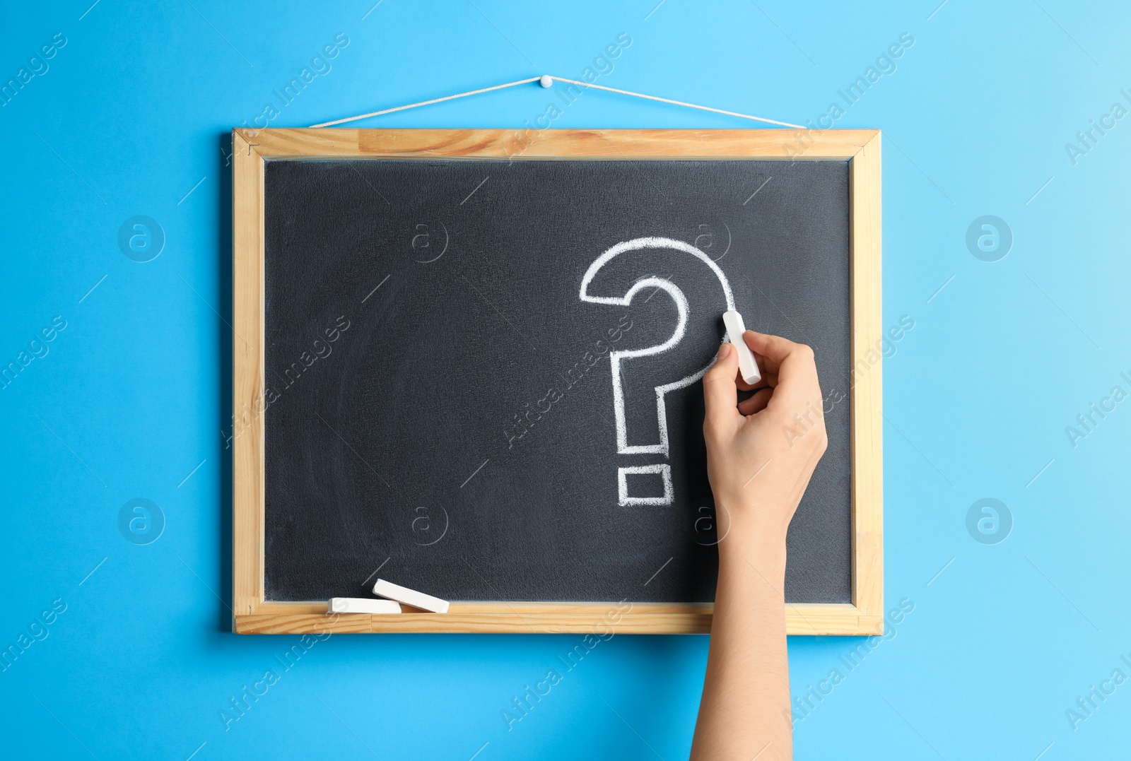 Photo of Woman writing question mark with chalk on blackboard, closeup