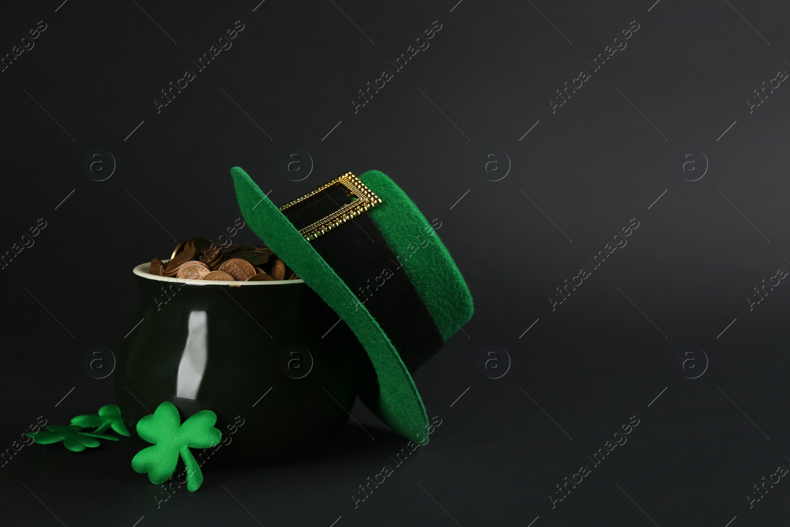 Photo of Pot of gold coins, hat and clover leaves on black background, space for text. St. Patrick's Day celebration