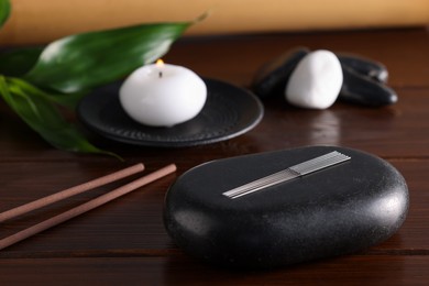 Acupuncture needles and spa stone on wooden table