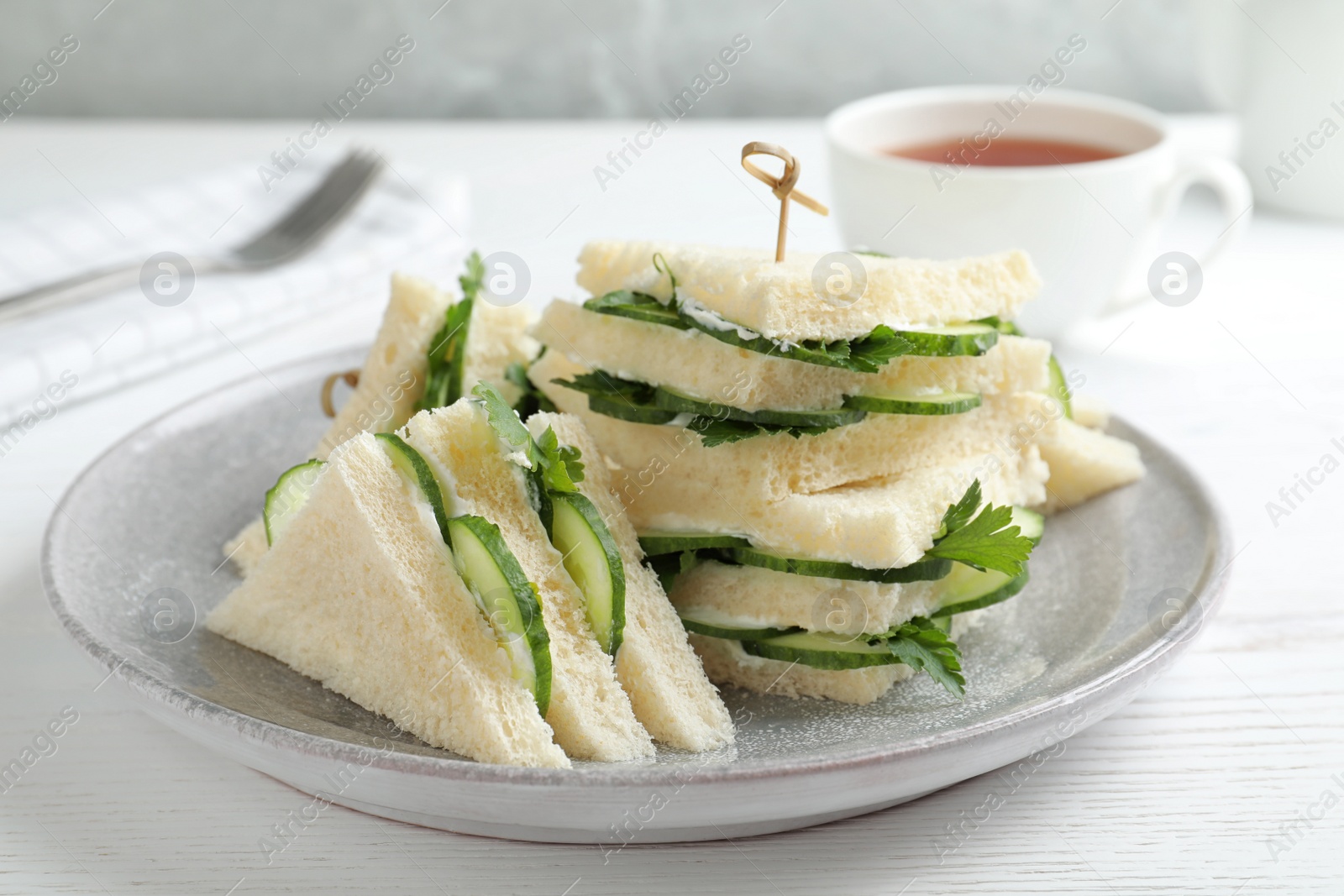 Photo of Plate with traditional English cucumber sandwiches on table