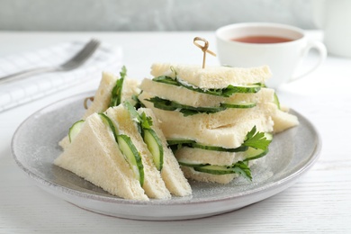 Photo of Plate with traditional English cucumber sandwiches on table