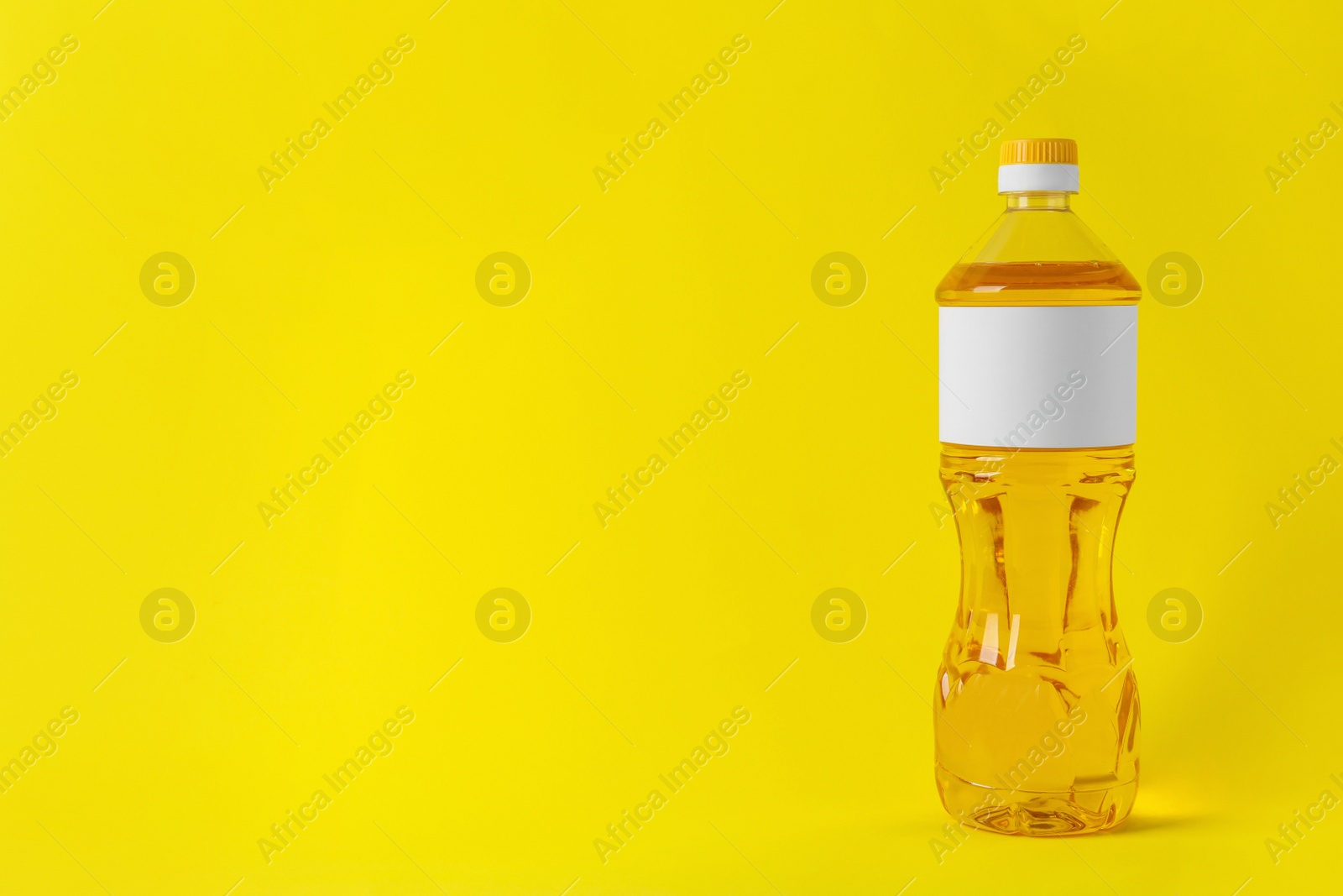 Photo of Bottle of cooking oil on yellow background. Space for text