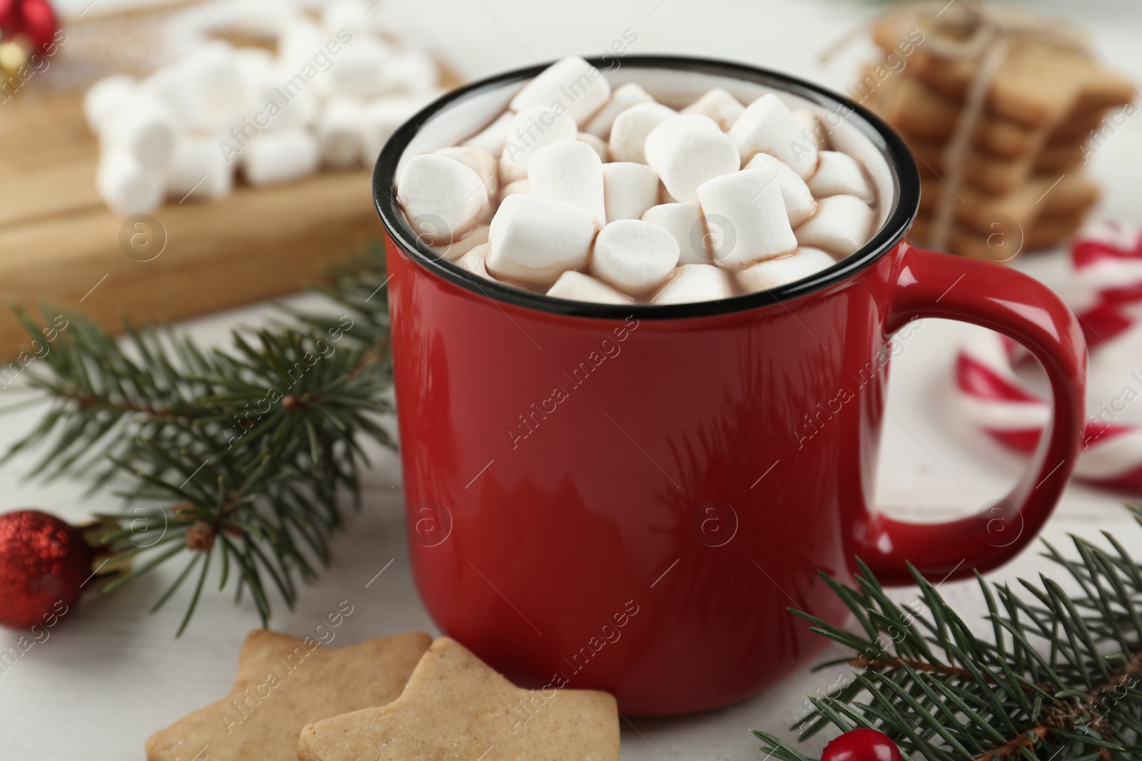 Photo of Hot drink with marshmallows in red cup on white table
