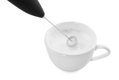 Photo of Whisking milk in cup with mini mixer (frother wand) isolated on white